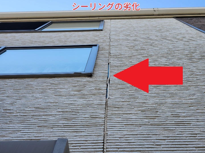 赤い矢印の部分が、ひび割れによるシーリングの劣化箇所。外壁目地の隙間が目視で確認できる。